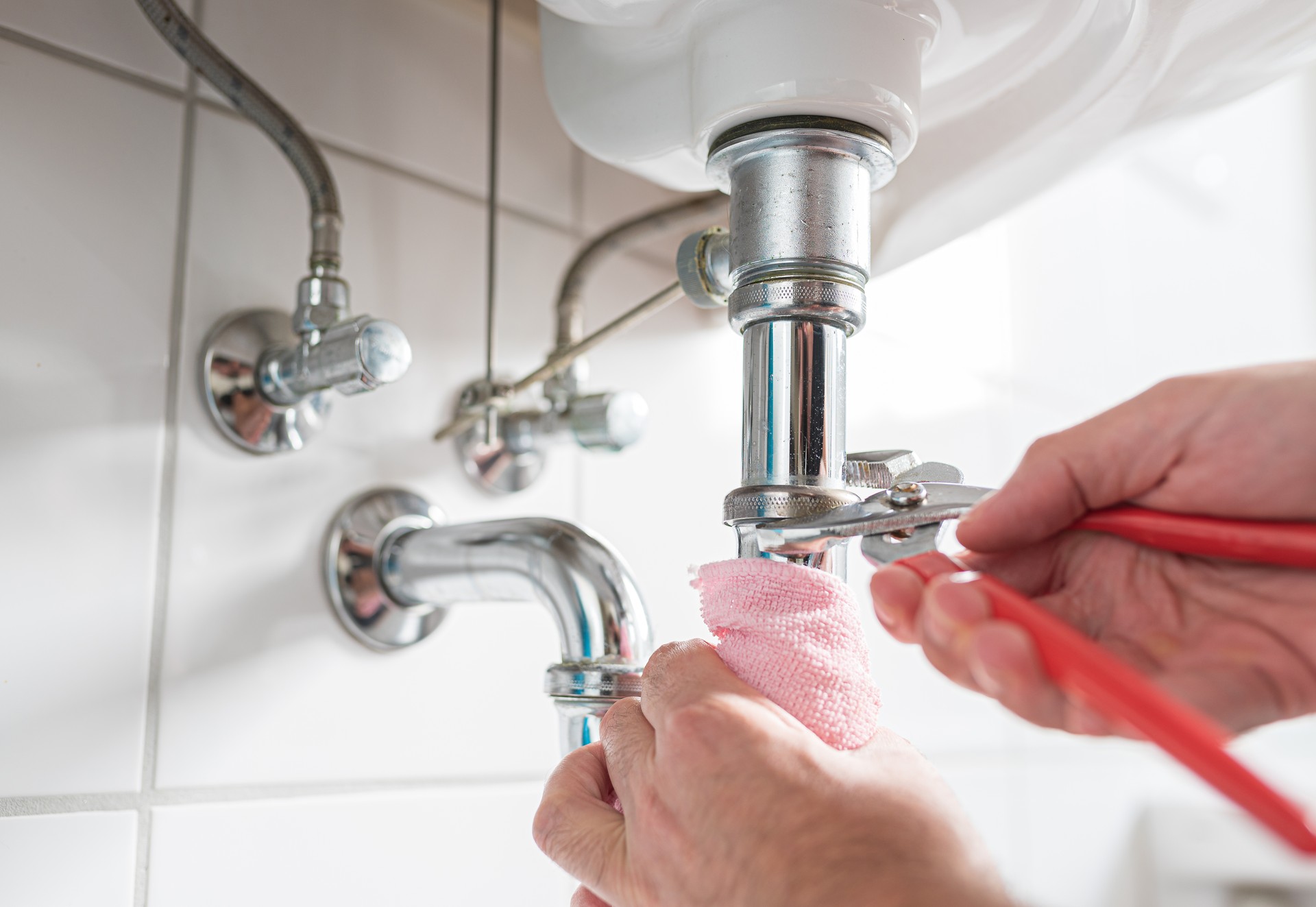 man repairing sink trap with adjustable pipe wrench